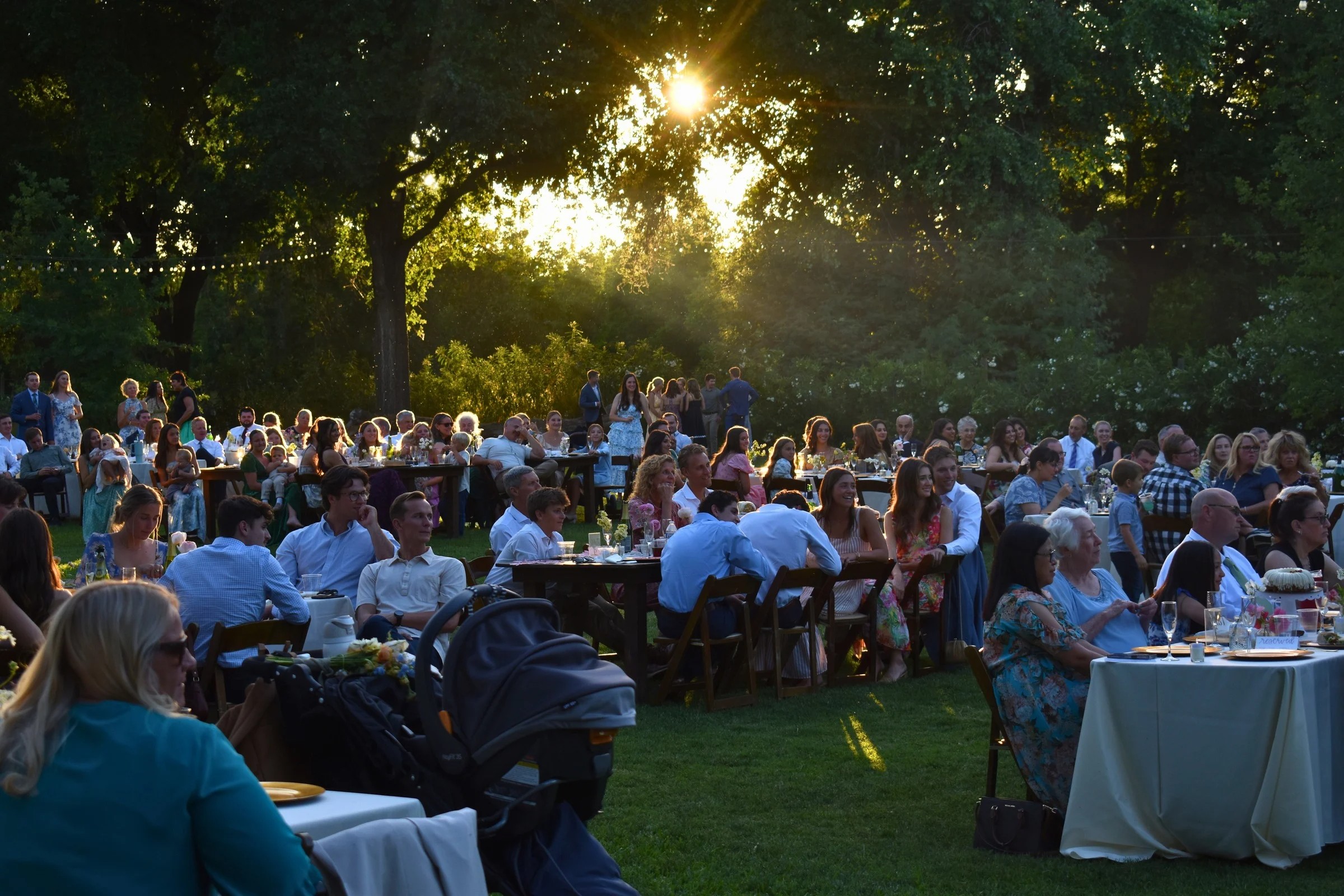 Golden hour outdoor wedding reception with guests and string lights